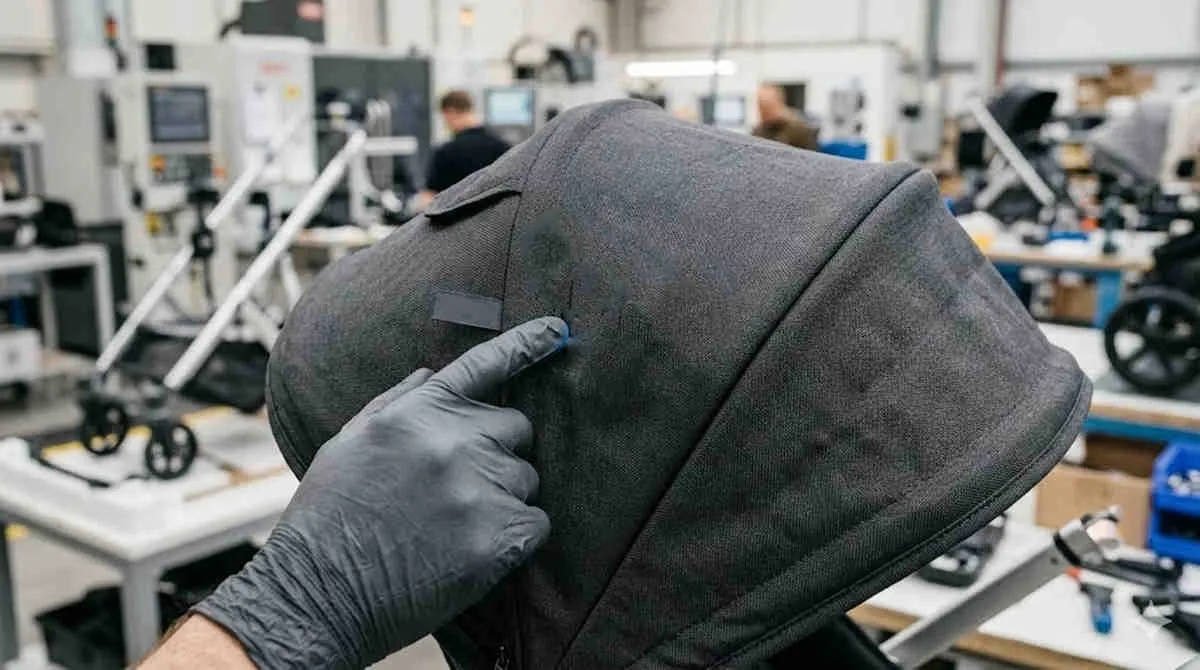 Baby Gear Replacement Cycle: Engineer points to a smart screen on stroller fabric in an R&D manufacturing facility.