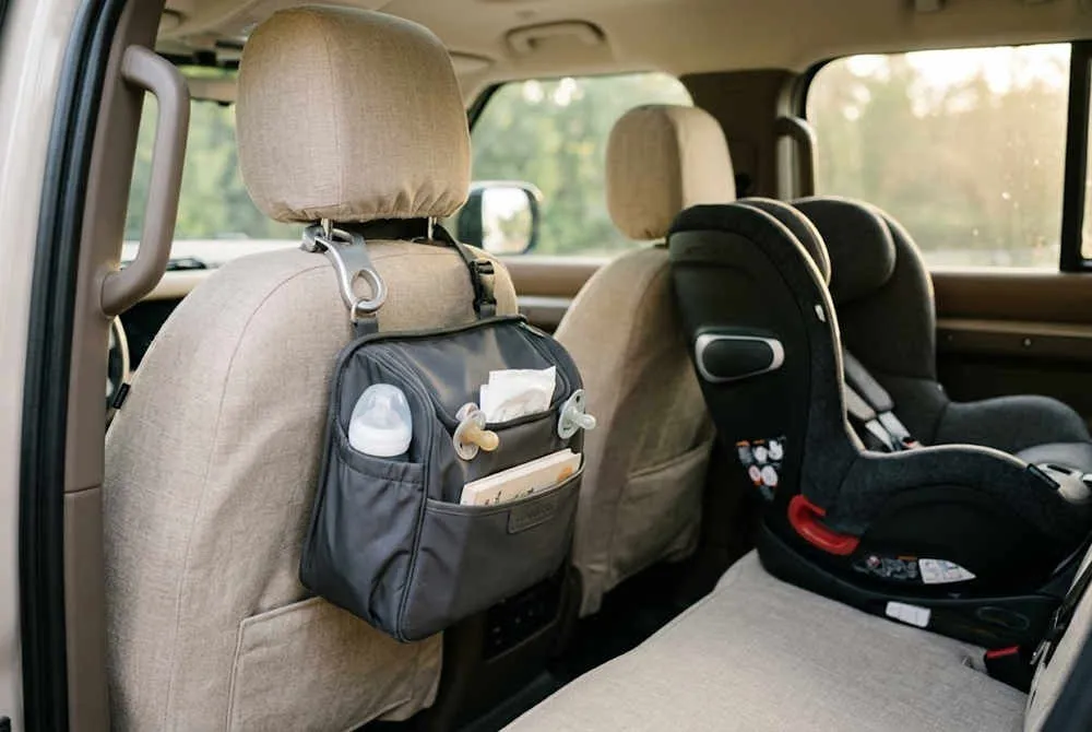 Wholesale baby travel accessories featuring a grey car backseat organizer bag with a baby bottle and pacifier inside.